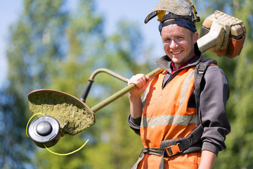 Portrait happy gardener man worker with gas grass trimmer equipment