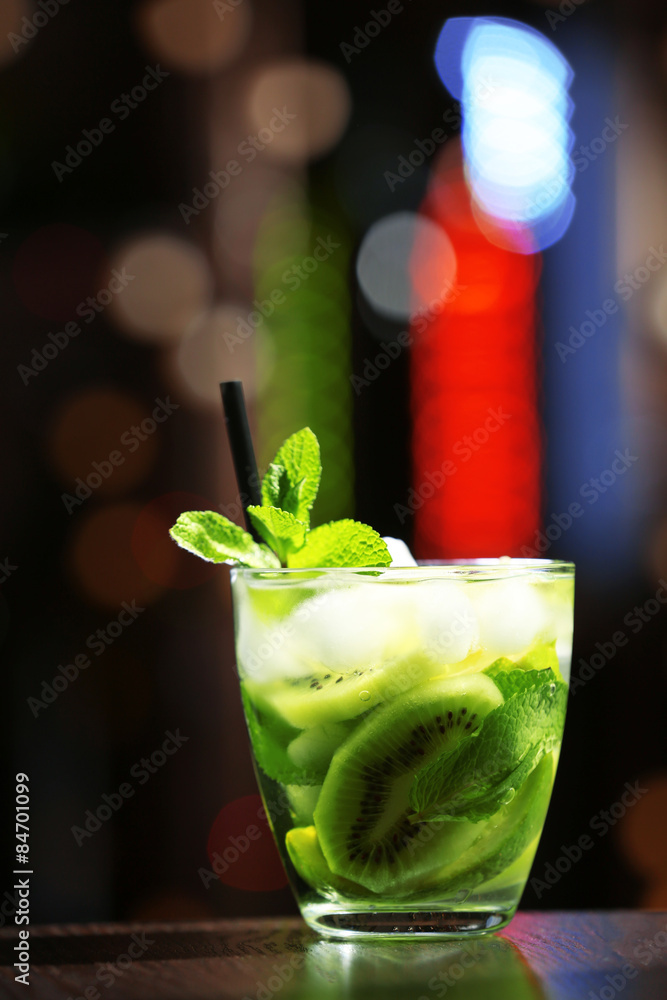 Glass of cocktail in bar on bright blurred background