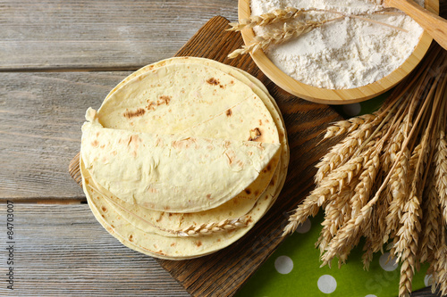 Fotografía Stack of homemade whole wheat flour tortilla on cutting board, on wooden table b