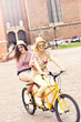 © Kalim - Two happy girl friends riding tandem bicycle