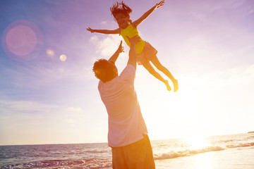 Father and little girl playing on the beach at the sunset