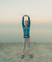 Wall Mural - Young woman stretching her arms on coast