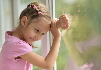 Wall Mural - Little girl standing near window