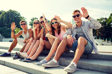 Wall Mural - group of smiling friends sitting on city street