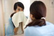 © Odua Images - Beautiful asian woman wiping her face with towel, looking at mir