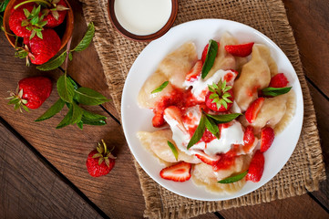 Fresh dumplings with strawberries and sour cream