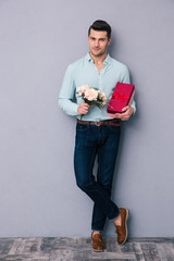 Poster - Happy young man holding gift box and flowers