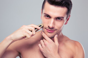 Handsome man shaving with electric razor