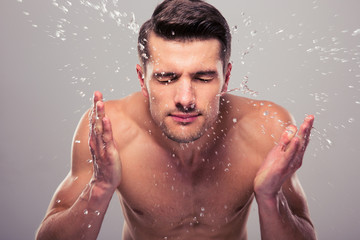 Young man spraying water on his face