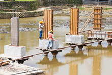 Workers Building Bridge Foundation Across Lake