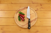 Red And Green Chilis With A Knife On A Chopping Board