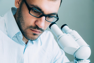 Wall Mural - young male doctor viewing through microscope