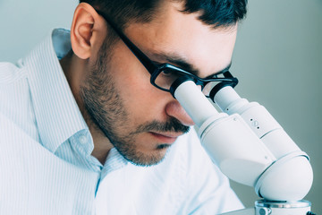 Wall Mural - young male doctor viewing through microscope
