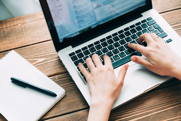 Woman working with laptop placed on wooden desk