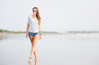 © x4wiz - Beautifil young woman walking along the beach at sunset enjoing