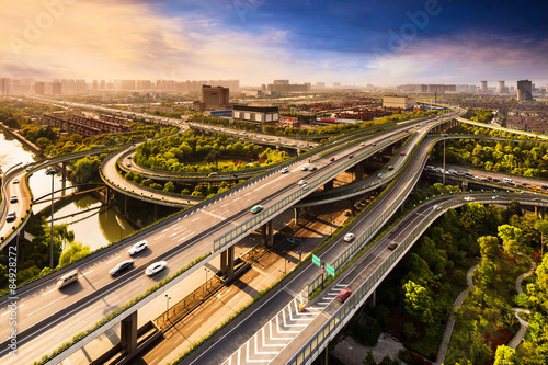 Fotomural Elevated overpass with skyline of modern city during sunset.