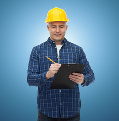 Canvas Print - smiling male builder in helmet with clipboard