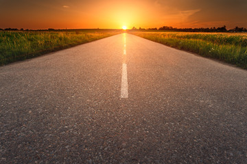 Canvas Print - Driving on an empty asphalt road at sunset