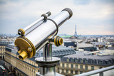 Fototapeta Paryż - Chrome telescope on the terrace of Lafayette galleries over Paris cityscape on background
