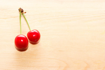 Two cherries isolated on background wooden table