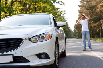 Man talking per mobile phone near car