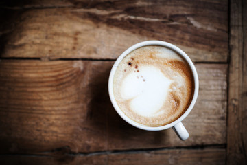 Poster - Cup of coffee with heart pattern in a white cup on wooden backgr
