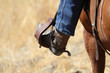 A close up view of a cowboy with his foot in the stirrup.