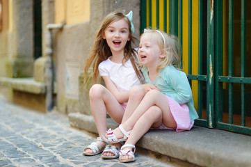 Two adorable little sisters laughing and hugging