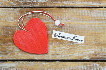 Wall Mural - because i care card with red wooden heart on rustic surface