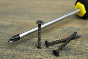 Working tools. Screwdriver and screws on wooden background