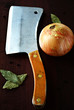 Vintage butchers knife, onion and bay leaves on brown wooden table. Cooking utensils
