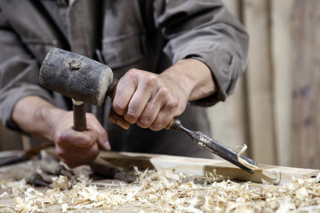 hands of carpenter with a hammer and chisel on the workbench in carpentry