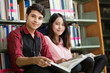 © torwaiphoto - Asian male and female students reading at library