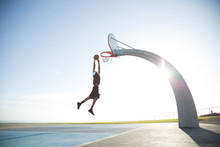 Man Dunking Basketball Into Hoop Against Clear Sky†