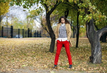 Young woman in fashion coat walking in autumn park