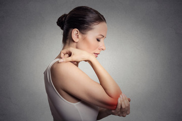 woman with painful elbow on gray background