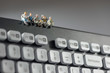 Miniature workers sitting on top of keyboard. Technology concept