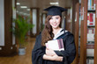 © zhu difeng - asian female student holding book and wearing academic dress in