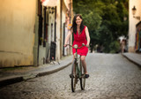 Fototapeta Miasto - Beautiful brunette girl on a vintage bike