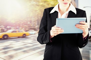 Poster - Composite image of redhead businesswoman using her tablet pc