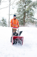 Man Using A Snow Blower To Clear A Driveway