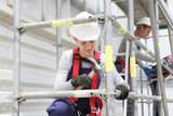 Fototapeta  - Young woman in professional training working on scaffolding