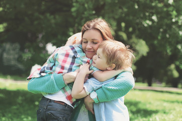 Family happiness! Happy mother tenderly embracing his two sons children in summer park