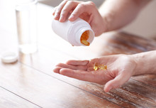 Close Up Of Man Pouring Fish Oil Capsules To Hand