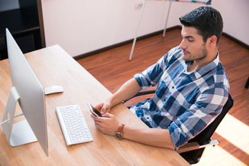 Poster - Businessman sitting at the table with smartphone