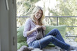 © Westend61 - Blond woman sitting on balcony knitting