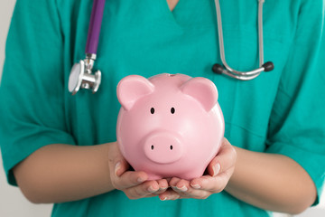 Female Doctor Holding Piggy Bank