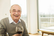 © Westend61 - Portrait of smiling senior man with glass of red wine