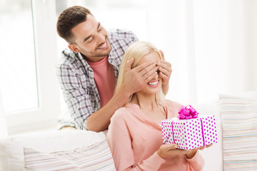 Wall Mural - happy man giving woman gift box at home