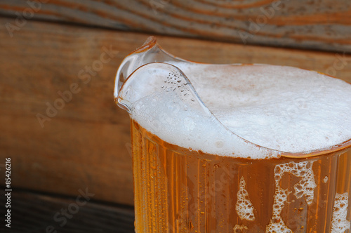 Fotografia, Obraz Closeup of Beer Pitcher with Wood Background